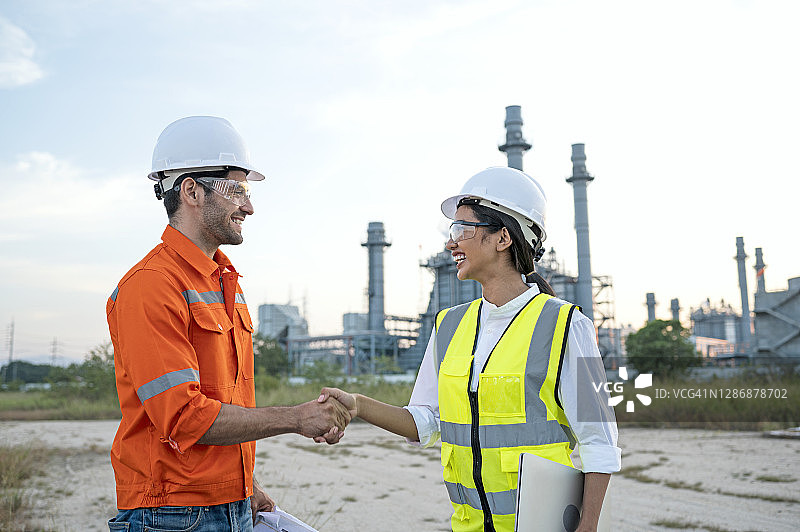 低角度拍摄的男土木工程师在建筑工地与女项目负责人握手图片素材