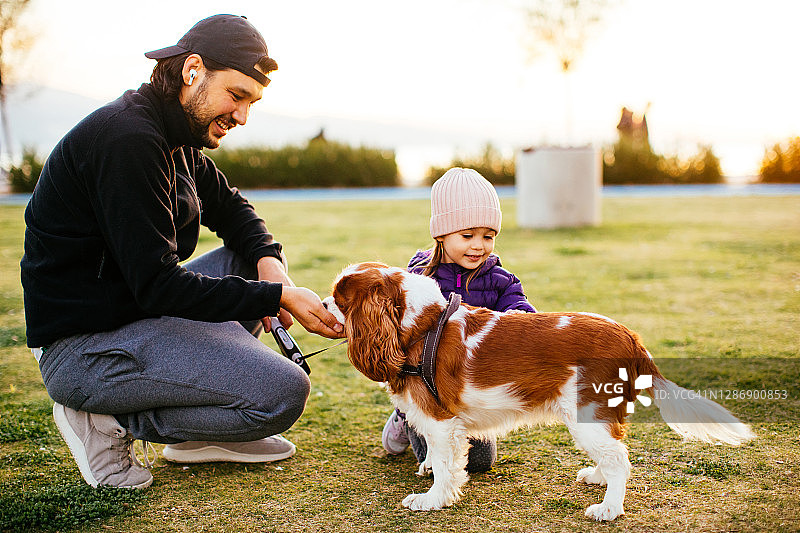 年轻的父亲和女儿与小狗在一起图片素材