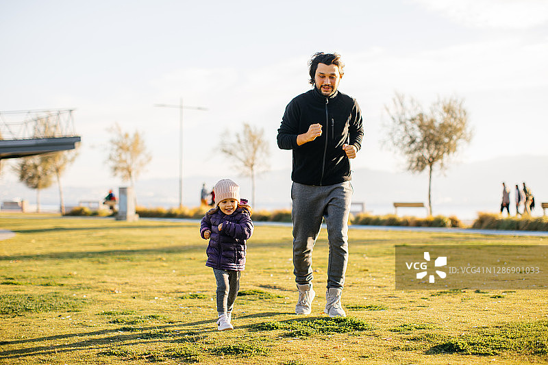 年轻男子和他的小女儿在公园里跑步图片素材