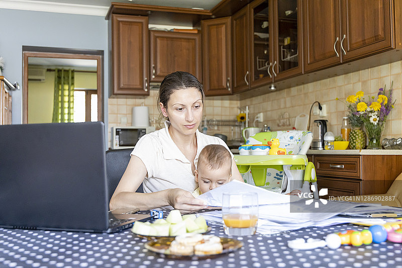 在家工作：职场妈妈边工作边看孩子图片素材
