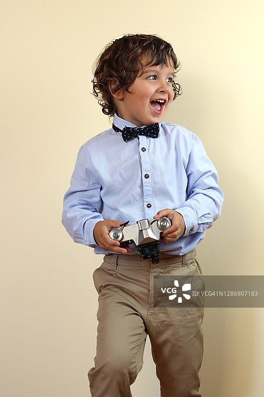 手里拿着老式相机的快乐微笑的男孩图片素材