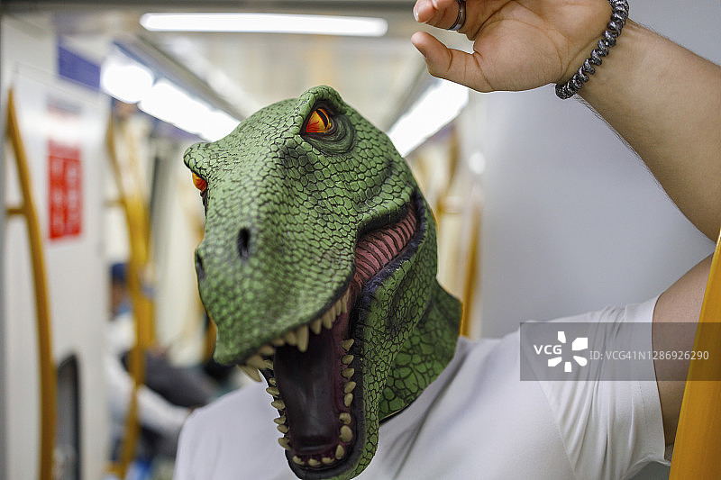 戴着恐龙面具乘坐火车的 мужчина图片素材