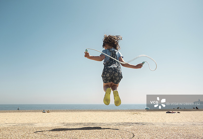 女孩在海滩上跳绳图片素材