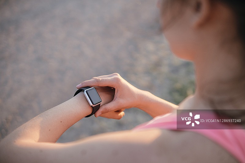 查看智能手表上的时间的健美年轻运动员图片素材