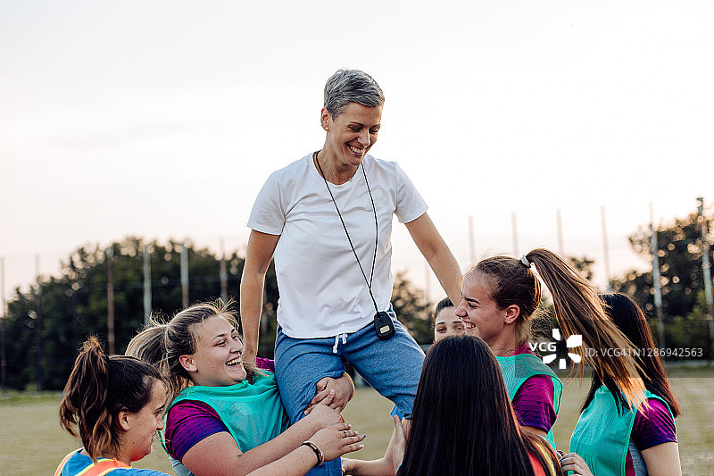 女子橄榄球队与教练一起庆祝胜利图片素材