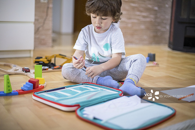 漂亮的小男孩用纸和蜡笔画画图片素材