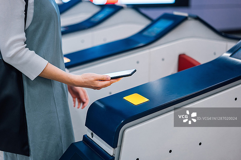 亚洲女性在地铁站用手机进行非接触式支付图片素材