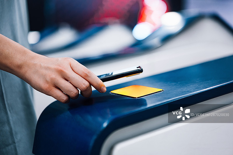 年轻亚洲女性在地铁站使用智能手机非接触式支付购买地铁票图片素材