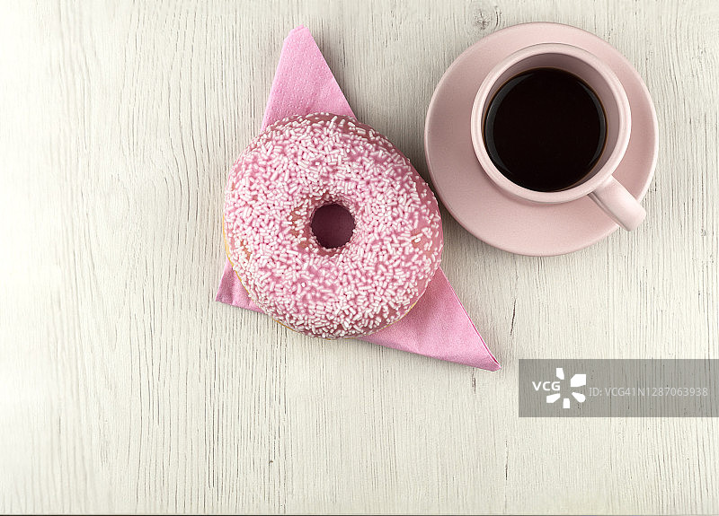 洒满白色糖屑的粉色甜甜圈和咖啡杯图片素材