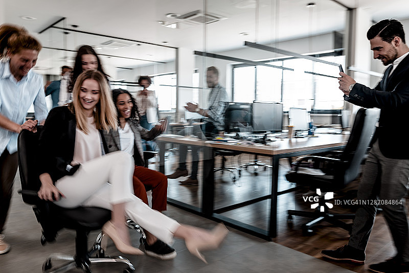 商务同事在办公室里用椅子赛跑图片素材