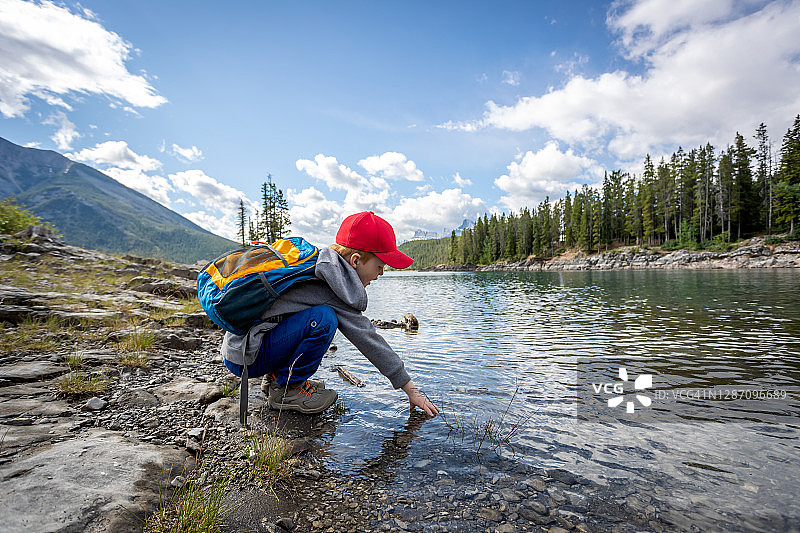 在班夫国家公园双杰克湖玩水的可爱红发小男孩图片素材