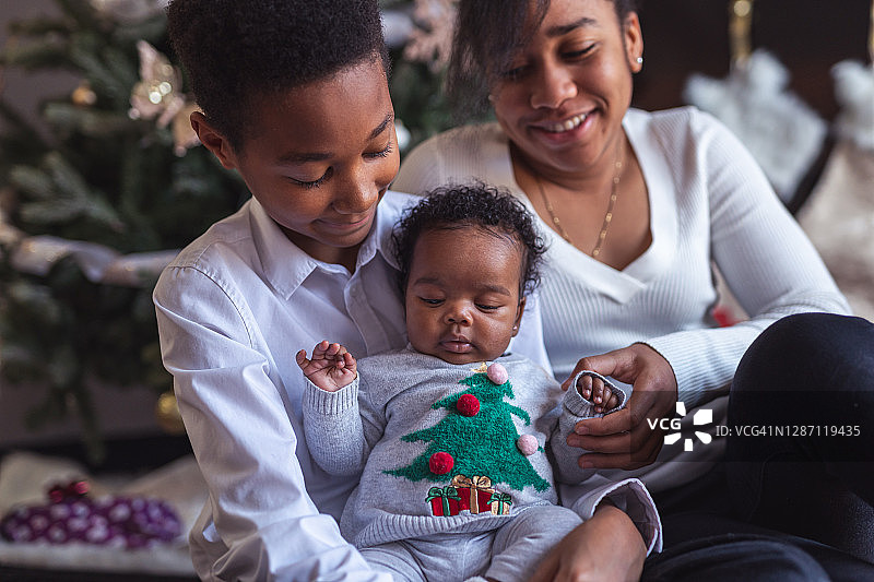 兄弟自豪地拥抱新生妹妹，圣诞前夜图片素材