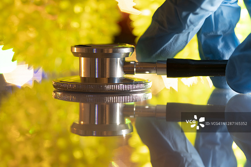 戴防护手套的人拿起听诊器，背景是冠状病毒图片素材