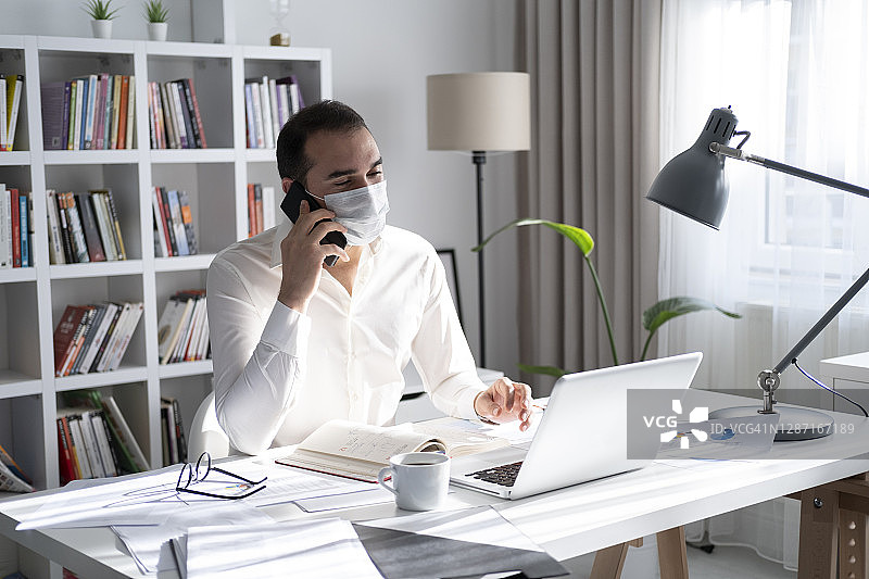 戴着健康口罩以预防新型冠状病毒感染的男人，在家工作和保持社交距离的概念图片素材