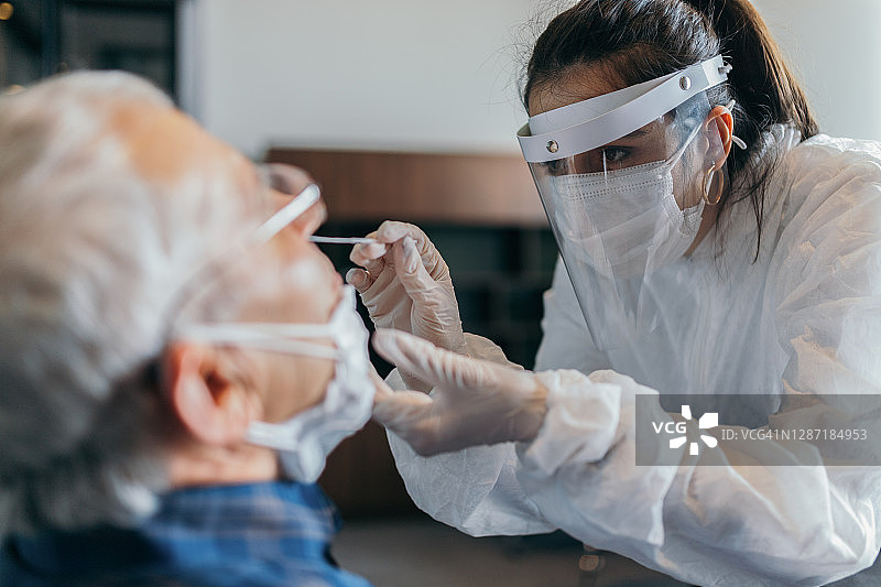 穿防护服的女医生为老年男子进行鼻拭子检测图片素材