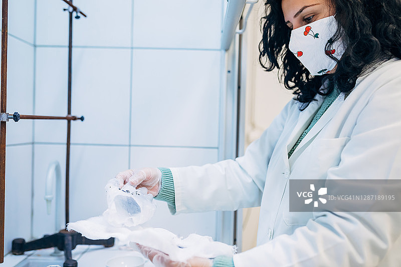 专业科学家观察石蜡手套并寻找证据痕迹的聚焦照片图片素材