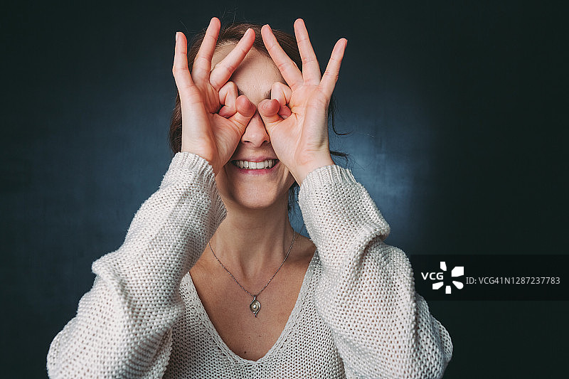 女人用手指遮住眼睛，寻找乐趣图片素材