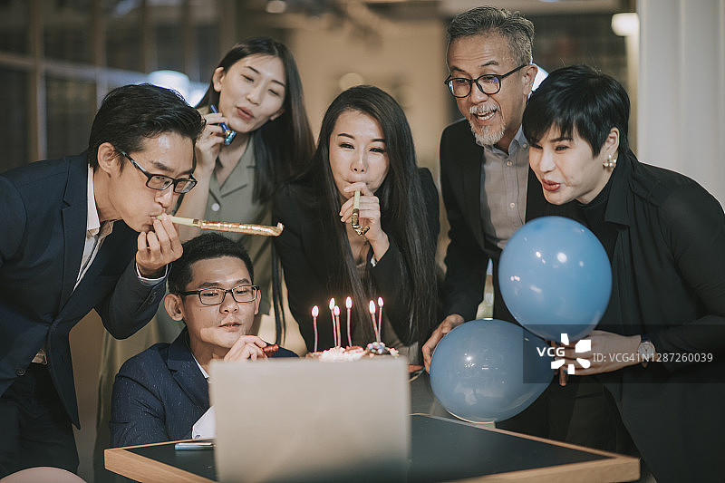 华人同事们通过笔记本电脑视频会议庆祝生日图片素材