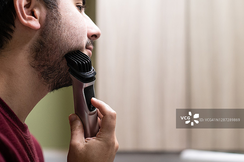年轻男人用电动剃须刀刮胡子图片素材