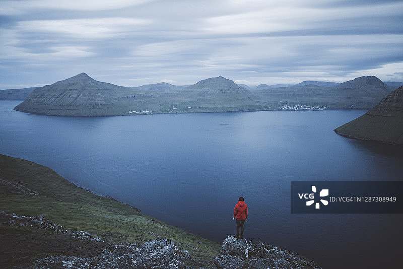 丹麦法罗群岛克拉克斯维克：站在岩石上眺望峡湾的女人图片素材