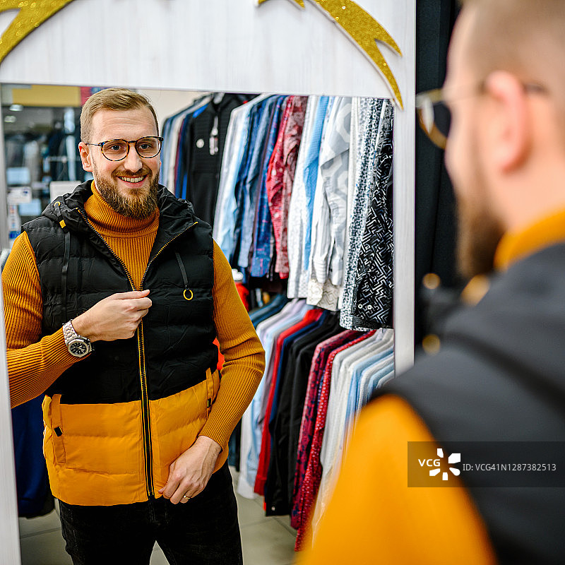 在百货商店购买衣服的面带笑容的男人图片素材