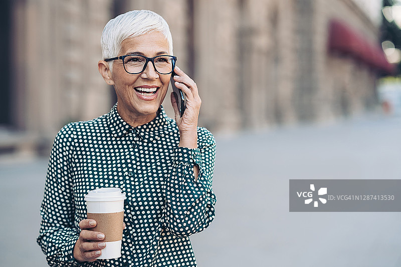 在街上打电话的微笑年长女商人图片素材