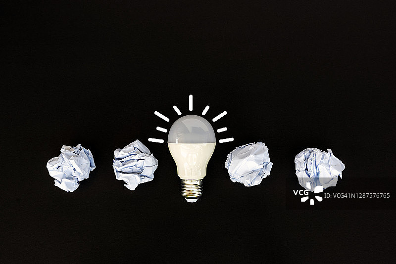 黑色背景上的白色灯泡和纸团图片素材