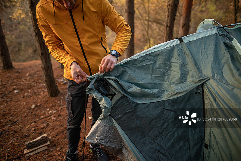 年轻男人在森林里搭帐篷图片素材