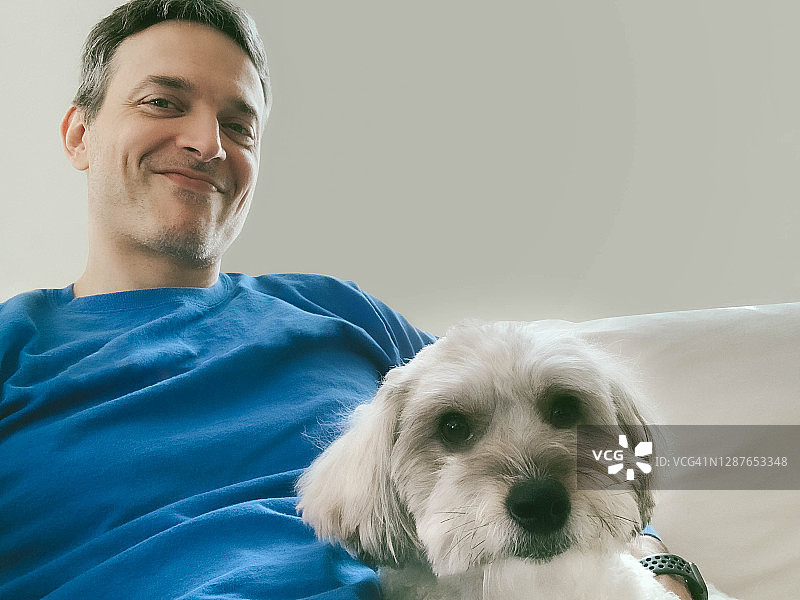 男人和他的狗一起坐在沙发上图片素材