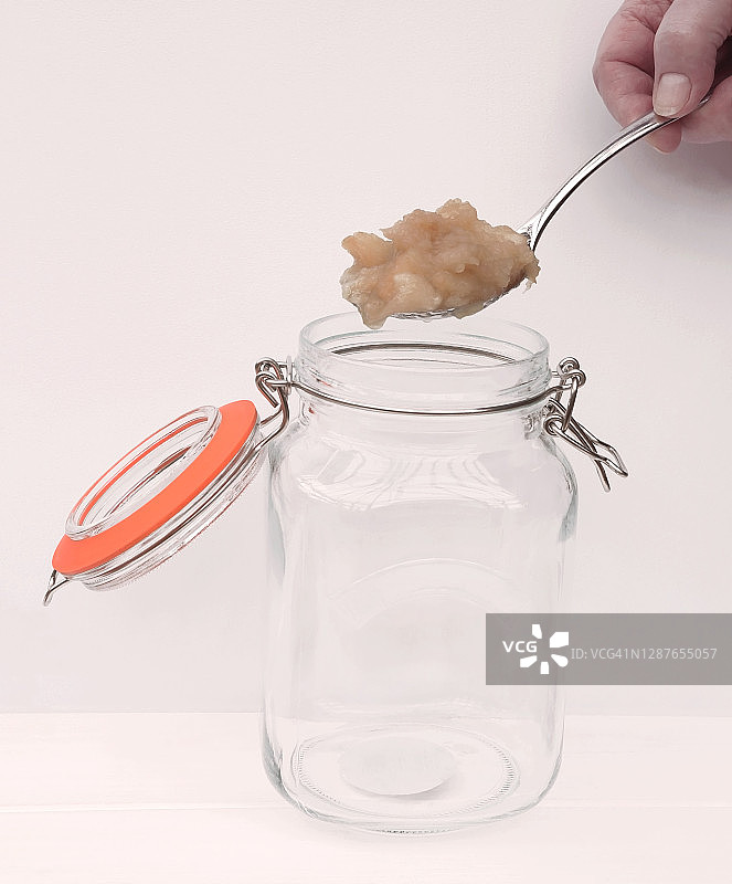 用勺子将炖苹果放入玻璃罐中图片素材