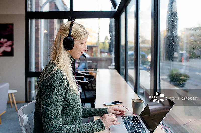 女人坐在咖啡馆里戴着耳机图片素材