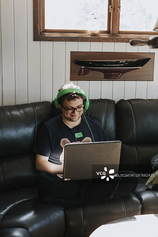 在沙发上用笔记本电脑的青少年男孩图片素材