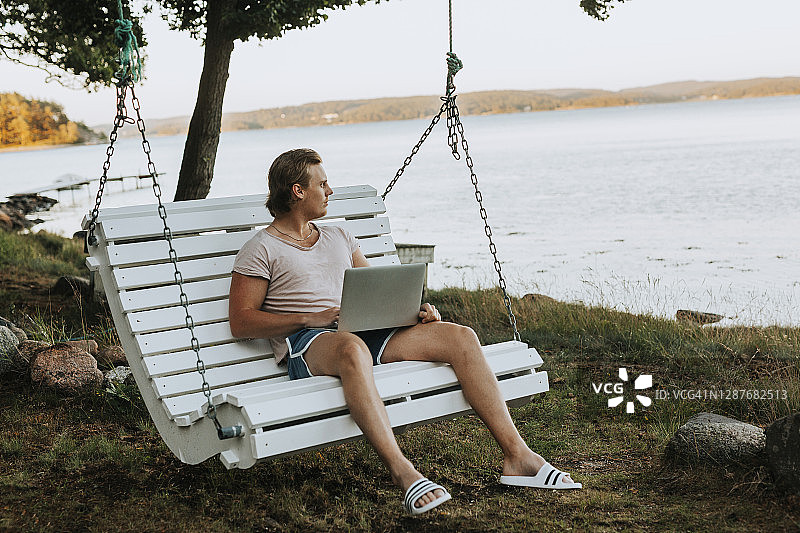 在花园秋千上眺望远方的男人图片素材