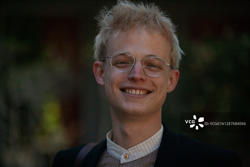 戴眼镜的英俊年轻人对着镜头微笑图片素材