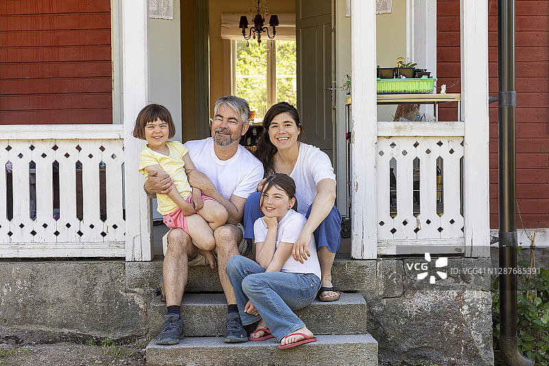 父母和两个女儿坐在房子前图片素材