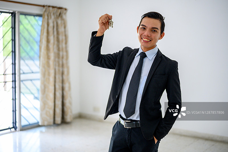 西装革履的成功房地产经纪人微笑并提供钥匙图片素材