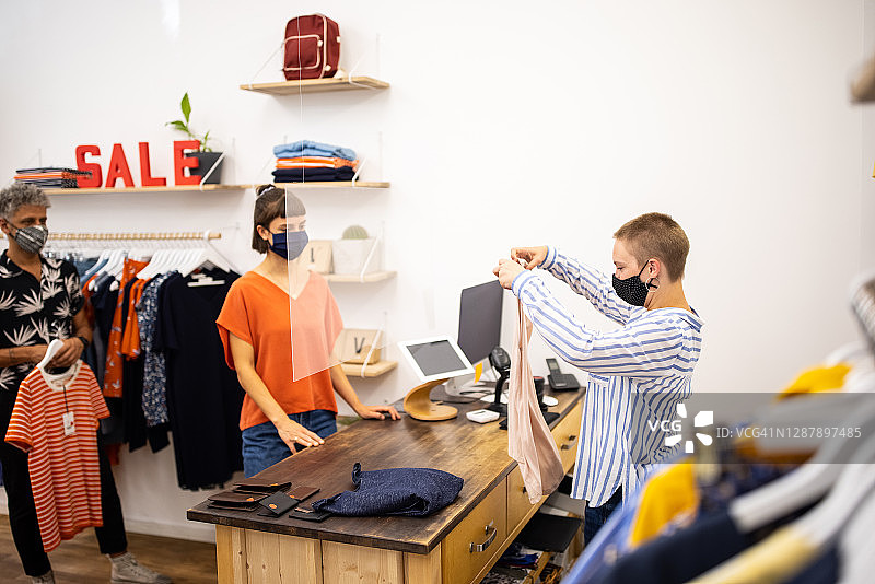 收银员在收银台折叠顾客购买的衣服图片素材