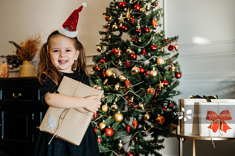 在圣诞树旁收到礼物的快乐小女孩图片素材