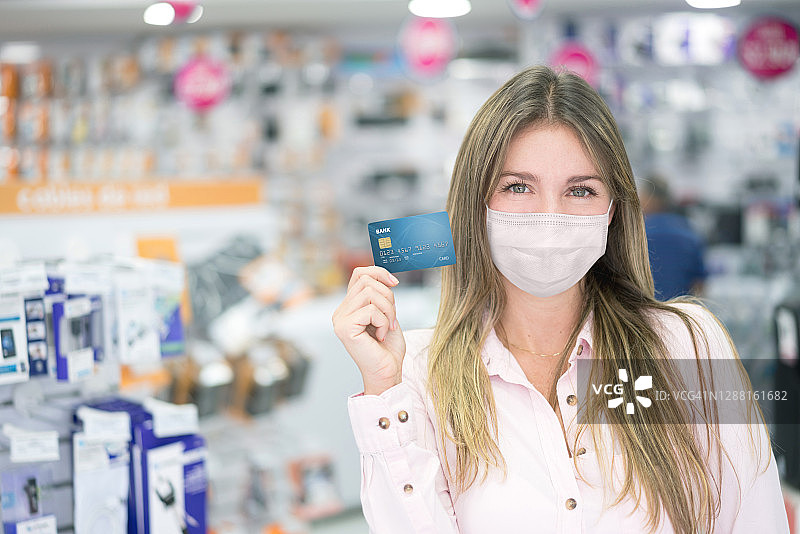戴着口罩的女子在科技商店用卡支付图片素材
