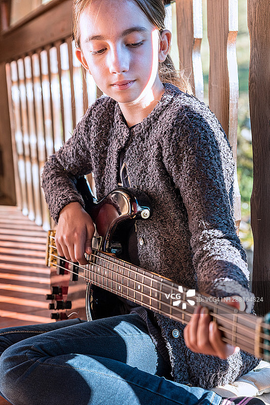 坐在阳台上练习弹贝斯吉他的女孩图片素材