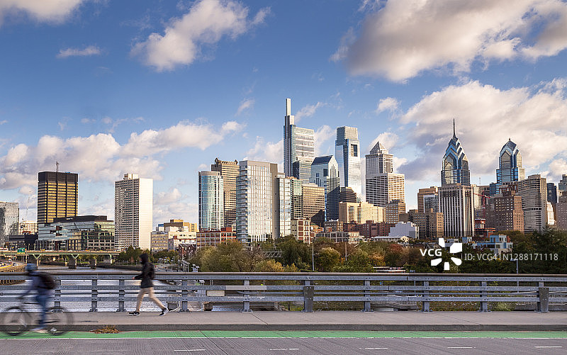 日落时分，骑行者和步行者在本·富兰克林大桥上欣赏费城天际线图片素材