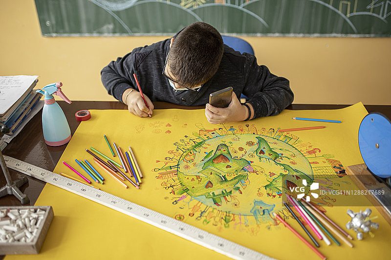 疫情期间，男孩在学校一边画画一边拿着手机图片素材