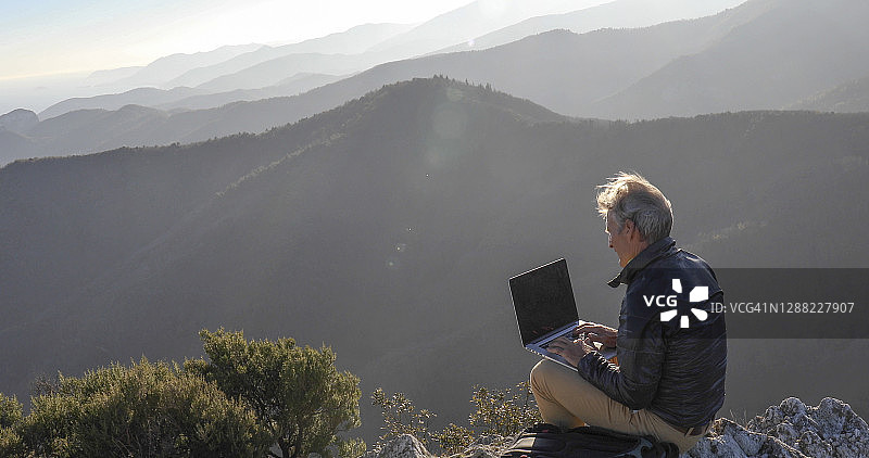 中年男人在日出时使用笔记本电脑图片素材