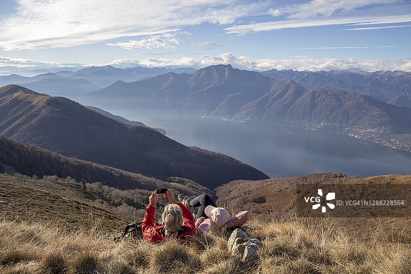 中年夫妇在山坡草地上放松并拍照图片素材
