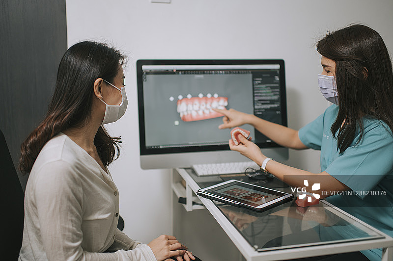 牙医向患者讲解3D牙齿模型图片素材