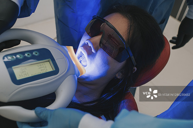 亚洲华人牙医为少女进行紫外线牙齿美白图片素材