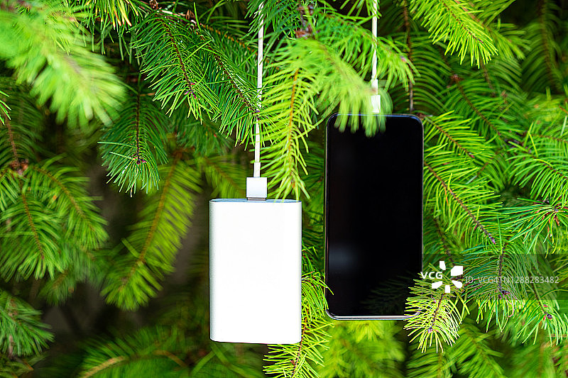 通过圣诞树背景上的设备共享电池，为移动智能手机无线充电图片素材