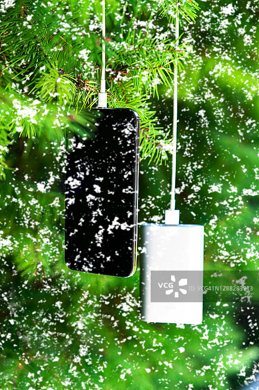 通过圣诞树背景上的设备共享电池，为移动智能手机无线充电图片素材