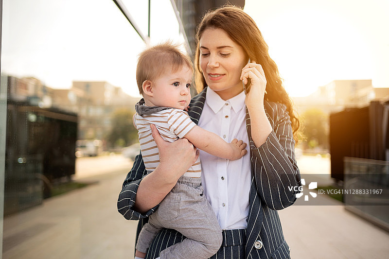 女人在户外抱着男婴进行商务通话图片素材