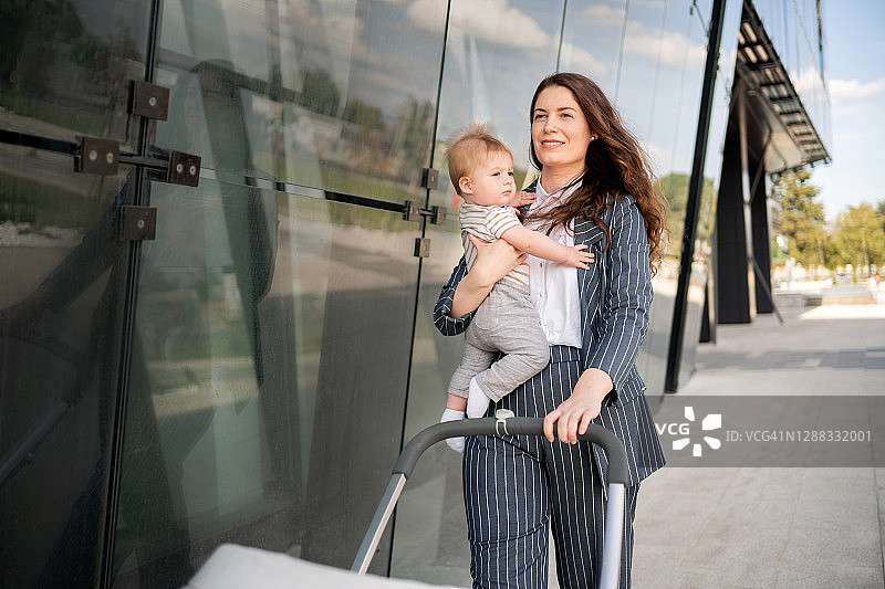 女人推着婴儿车，抱着她的男婴图片素材